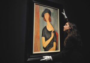 (FILES) In a file picture taken on February 1, 2013 a member of staff poses next to a work entitled ''Jeanne Hebuterne (au chapeau)' by Italian artist Amedeo Modigliani at Christies auction house in central London. The 1919 portrait by Modigliani of his lover Jeanne Hebuterne went under the hammer in London on February 6, 2013 for 26.9 million GBP (42.3 million USD, 31.2 million euros), well above the the pre-sale estimate of between 16 and 22 million GBP. AFP PHOTO / CARL COURT